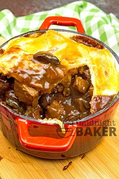 a pot filled with meat and vegetables on top of a wooden cutting board