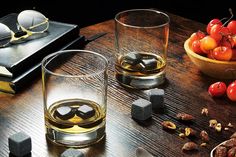 two glasses filled with liquid sitting on top of a wooden table next to other items