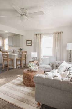 a living room filled with furniture next to a kitchen and dining room table on top of a rug