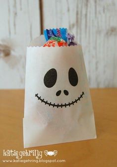 a paper bag with a skeleton face on it and candy in its mouth is sitting on a table