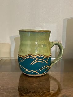 a green and blue mug sitting on top of a table