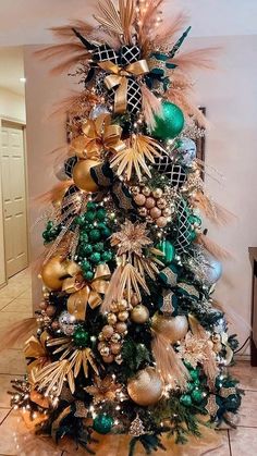 a decorated christmas tree with gold, green and silver ornaments on it's base