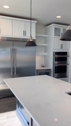 a large kitchen with stainless steel appliances and white cabinets, along with an island in the middle