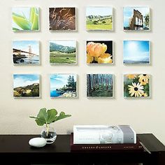 there are many pictures hanging on the wall next to a vase with flowers in it