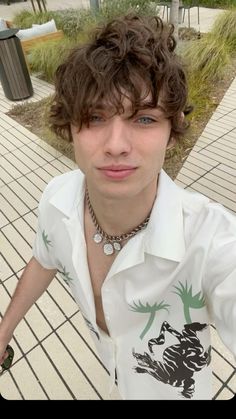 a young man with curly hair wearing a white shirt