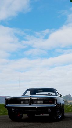 an old car is parked on the side of the road with a kite flying in the sky