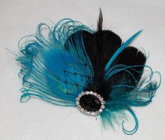 there is a blue and black feather on the white tablecloth with a crystal brooch