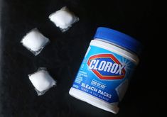 several pieces of ice sitting on top of a black table next to a can of clorox