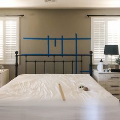 a white bed with blue tape on the headboard and foot board in a bedroom