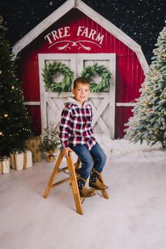 a young boy sitting on a stool in front of a christmas tree and farm sign