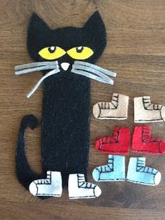 a paper cut out of a black cat sitting on top of a wooden table next to two pairs of shoes