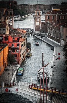 boats are in the water next to buildings and a bridge with a clock on it