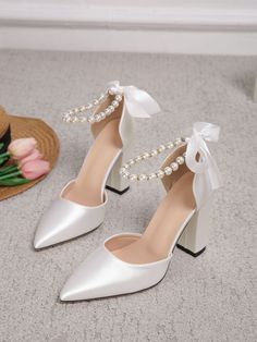 a pair of white high heels with pearls on the toe and heel, sitting next to a