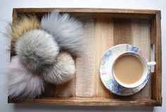 a cup of coffee and a furry animal on a tray