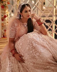 a woman in a wedding dress sitting on the floor with her hands behind her head