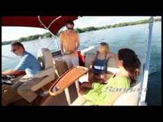 four people are sitting on the back of a boat in the water while one person is talking