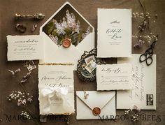 the wedding stationery is laid out on top of each other, including an envelope and two wax stamp stamps