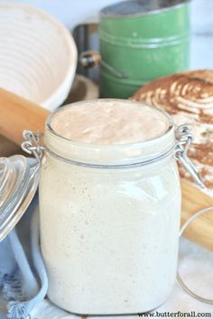 a glass jar filled with white liquid sitting on top of a counter next to baking utensils