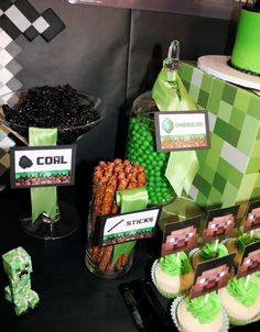 a table topped with cupcakes and cakes covered in green frosted icing