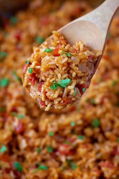 a wooden spoon filled with rice and peas