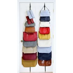 several purses hanging on hooks in front of a white door with multiple colors and sizes