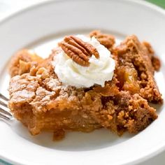 a piece of pie on a white plate with whipped cream and pecans in the middle