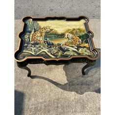 an ornately painted table with two leopards on it's sides, sitting on the ground