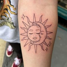 a sun and moon tattoo on the left arm, with eyes closed to the side