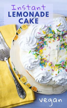 a cake with white frosting and sprinkles on it, next to a yellow napkin