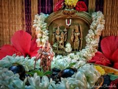 an arrangement of flowers and figurines is displayed in front of a decorative frame