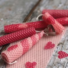 three red candles with hearts on them sitting on a piece of pink paper next to a key