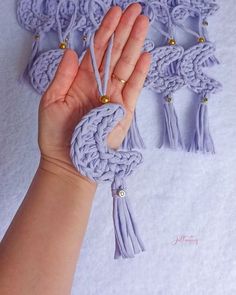 a hand is holding some tassels in front of a white background with gold beads