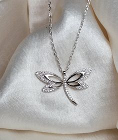 Brilla con elegancia atemporal. Nuestro collar de libélula de plata 925, adornado con brillantes diamantes de imitación Zirconias Cúbicas es el accesorio perfecto para cada ocasión. Elegant Sterling Silver Dragonfly Necklace, Elegant Sterling Silver Dragonfly Jewelry, Elegant Silver Dragonfly Jewelry, Silver Necklace With Rhinestones For Gift, White Dragonfly Jewelry Gift, Elegant Dragonfly Jewelry For Wedding, Silver Dragonfly Jewelry, Sterling Silver Dragonfly Necklace, Jewelry Care Instructions