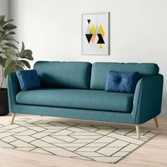 a blue couch sitting on top of a wooden floor next to a potted plant