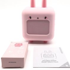 a pink toy with two ears on it next to a box and some other items