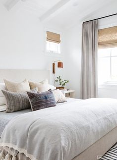 a bed with white linens and pillows in a bedroom