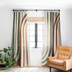 a chair sitting in front of a window next to a potted plant on top of a rug