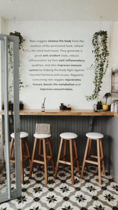 three stools in front of a bar with plants growing on the wall behind it