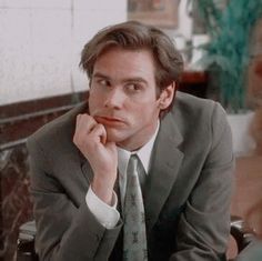 a man in a suit and tie sitting at a table with his hand on his chin