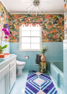 a bathroom with blue tile and floral wallpaper on the walls, along with a white toilet and bathtub