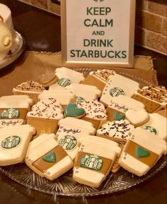 some cookies are on a glass plate and there is a sign that says keep calm and drink starbucks