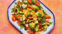 a blue and white plate filled with food on top of a pink tablecloth next to an orange wall