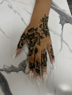 a woman's hand painted with black and white flowers on her left palm, sitting on a marble countertop