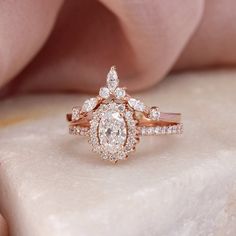 a close up view of a diamond ring on a stone surface with pink fabric in the background