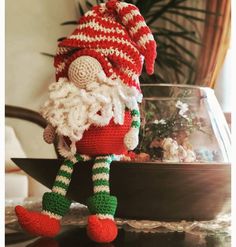 a crocheted santa clause doll sitting on top of a table next to a potted plant