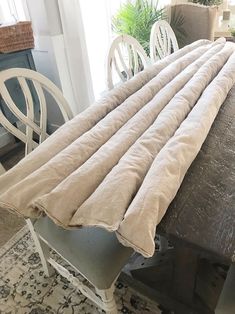 a dining room table with chairs and a blanket on it's backrests