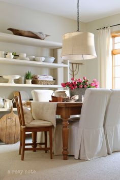 the dining room table is covered with white linens and has pink flowers on it