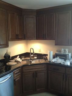 a kitchen with dark wood cabinets and black counter tops is lit by light coming through the window