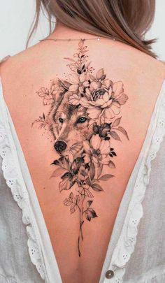 the back of a woman's neck with flowers and a wolf