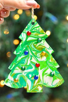 a hand holding a green and white christmas tree ornament